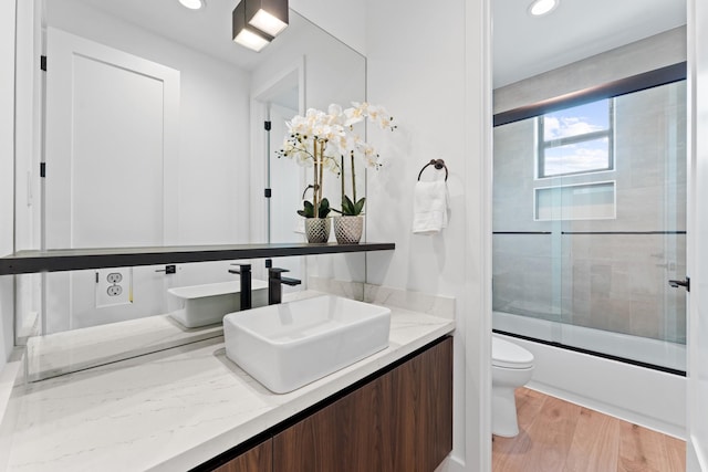 full bathroom featuring vanity, toilet, recessed lighting, combined bath / shower with glass door, and wood finished floors