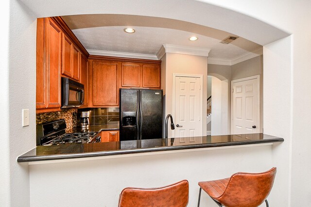 1708 Aden Mist Dr, Houston, TX 77003 - kitchen with black appliances, ornamental molding, arched walkways, a peninsula, and dark countertops