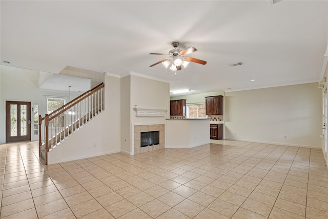 unfurnished living room with a fireplace, light tile patterned flooring, ceiling fan, stairs, and visible vents