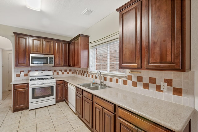 kitchen featuring light countertops, visible vents, a sink, and white appliances