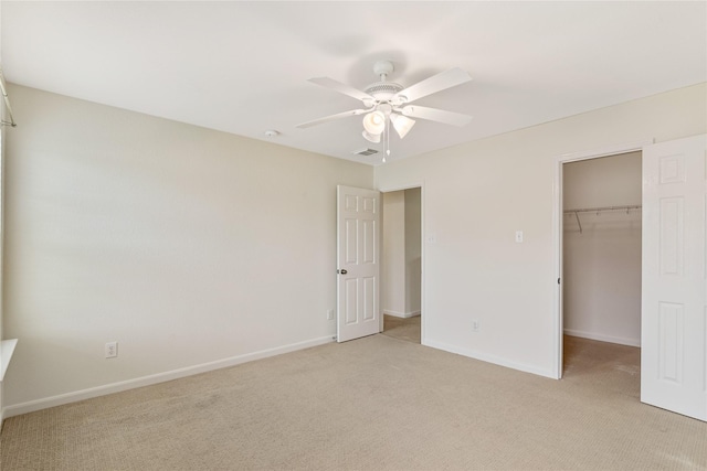 unfurnished bedroom featuring light colored carpet, visible vents, a spacious closet, and baseboards