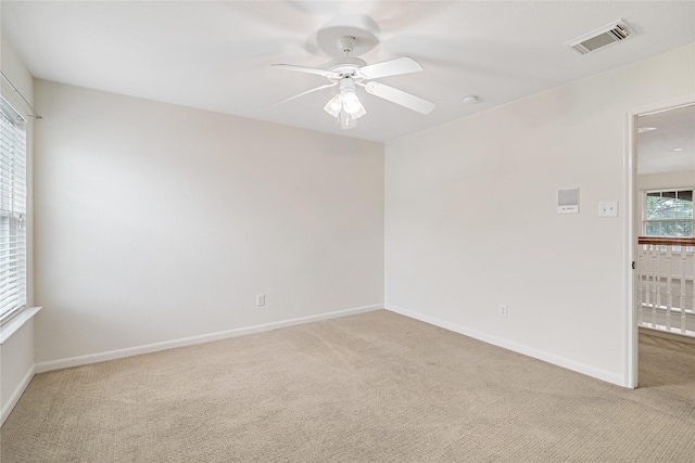 unfurnished room featuring baseboards, visible vents, ceiling fan, and light colored carpet