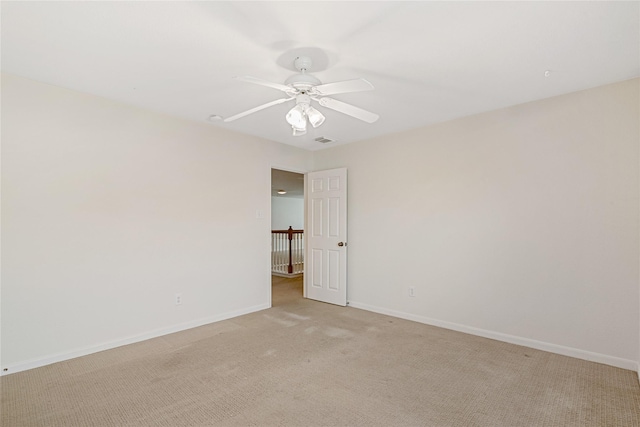 spare room featuring light colored carpet, visible vents, ceiling fan, and baseboards