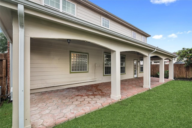 rear view of house featuring a patio, a yard, and fence