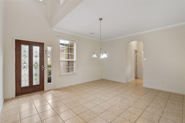 foyer entrance with light tile patterned floors, arched walkways, a notable chandelier, and crown molding