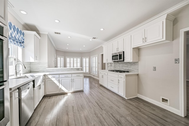 3430 Williams Glen Dr, Sugar Land, TX 77479 - kitchen featuring appliances with stainless steel finishes, light countertops, backsplash, light wood-style flooring, and ornamental molding