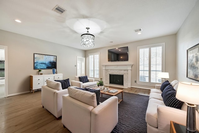 3430 Williams Glen Dr, Sugar Land, TX 77479 - living room featuring a fireplace with flush hearth, wood finished floors, baseboards, recessed lighting, and a chandelier