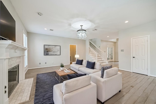 3430 Williams Glen Dr, Sugar Land, TX 77479 - living area with light wood-style floors, a chandelier, stairs, a tiled fireplace, and baseboards