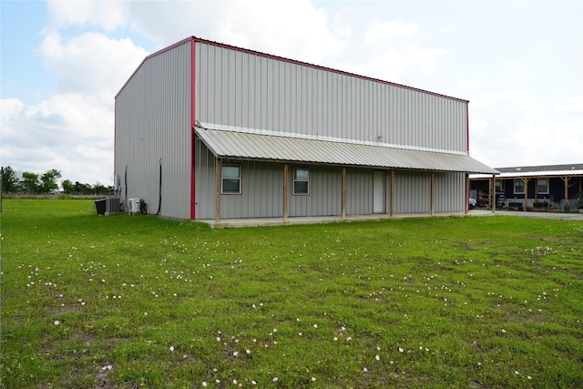 rear view of property featuring an outbuilding, an outdoor structure, a yard, and metal roof