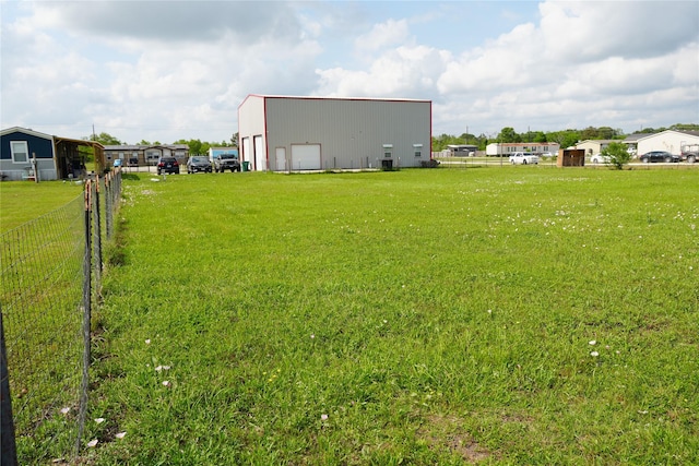 view of yard featuring fence, a pole building, an outdoor structure, and a garage