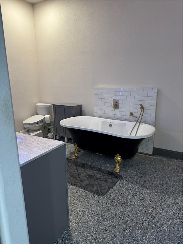 bathroom with vanity, speckled floor, a freestanding bath, and toilet