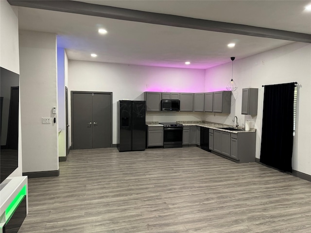 kitchen with gray cabinetry, light countertops, black appliances, and light wood finished floors