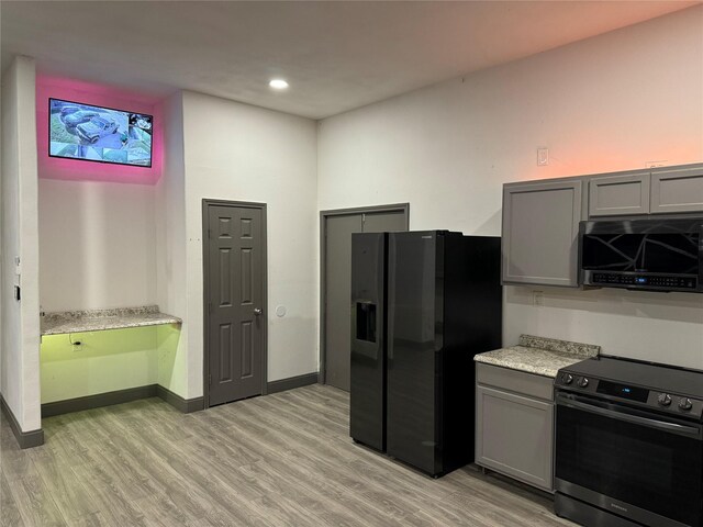 kitchen featuring light wood-style floors, gray cabinetry, black fridge, and electric stove