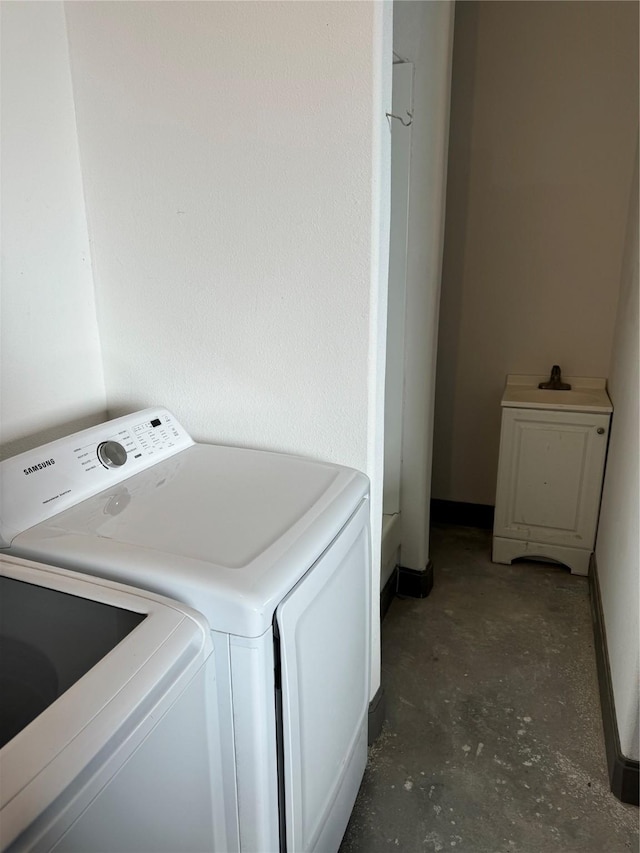 clothes washing area featuring baseboards, a sink, washing machine and dryer, and laundry area