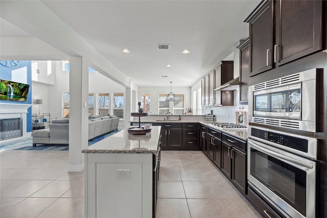 3419 Marlene Meadow Way, Richmond, TX 77406 - kitchen with stainless steel appliances, light stone countertops, a sink, a kitchen island, and light tile patterned floors