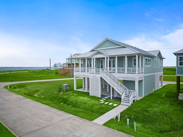 coastal inspired home featuring a front lawn, metal roof, and stairs