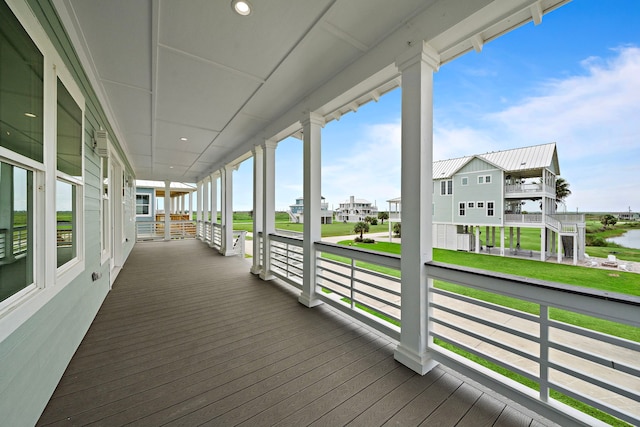 wooden terrace featuring a porch, a yard, a residential view, and a water view