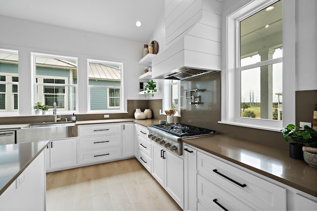 kitchen with white cabinetry, open shelves, a sink, appliances with stainless steel finishes, and dark countertops