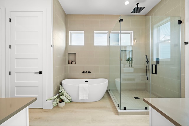 full bath with a healthy amount of sunlight, vanity, a shower stall, and tile walls