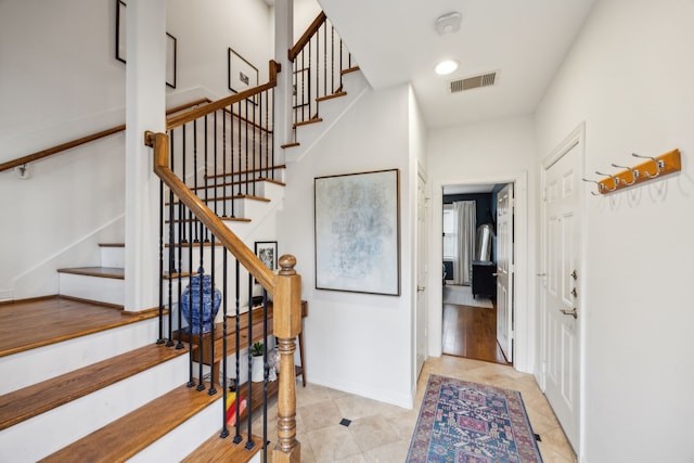 staircase with tile patterned floors, baseboards, and visible vents