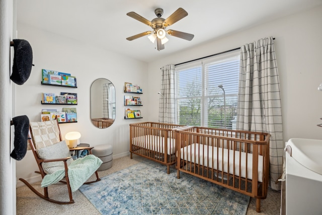 bedroom featuring baseboards, a ceiling fan, and a nursery area