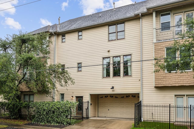 back of property featuring fence, an attached garage, and concrete driveway