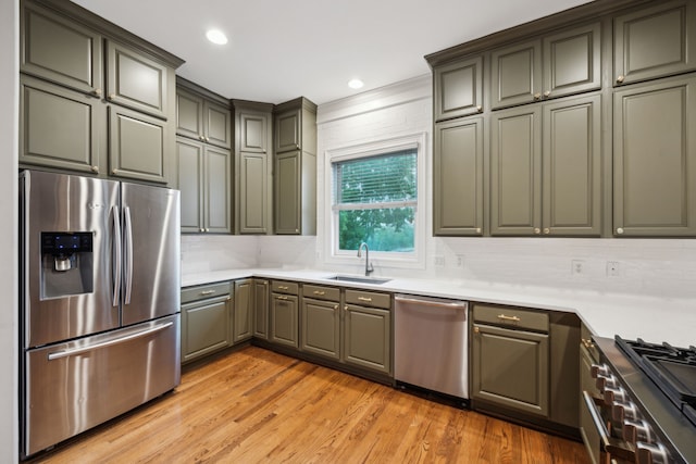 kitchen featuring a sink, light wood finished floors, appliances with stainless steel finishes, backsplash, and gray cabinetry