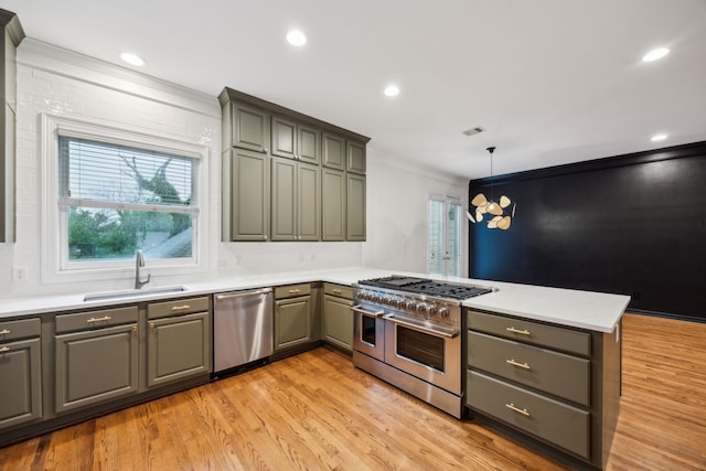 kitchen featuring a sink, light wood-style floors, stainless steel appliances, a peninsula, and gray cabinetry