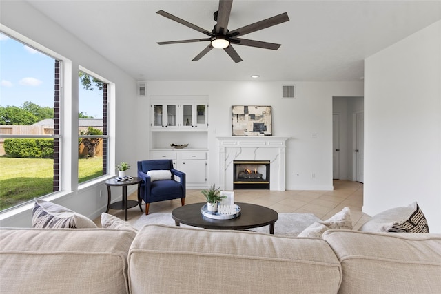 living area with a high end fireplace, light tile patterned flooring, visible vents, and ceiling fan