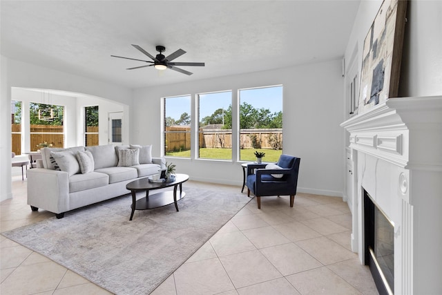 living room with light tile patterned floors, a ceiling fan, baseboards, and a fireplace