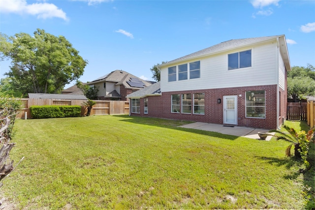 back of property featuring brick siding, a fenced backyard, a yard, and a patio area