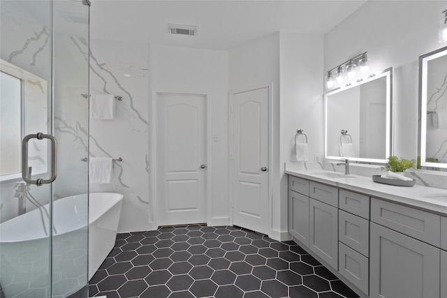 full bathroom with a freestanding tub, visible vents, vanity, and tile patterned floors