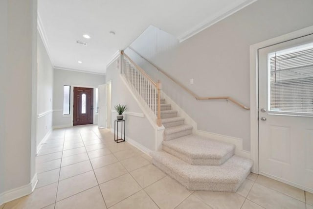 entrance foyer featuring light tile patterned floors, stairway, visible vents, baseboards, and ornamental molding