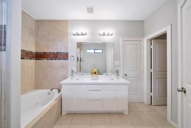bathroom with tile patterned floors, a tub with jets, double vanity, and a sink