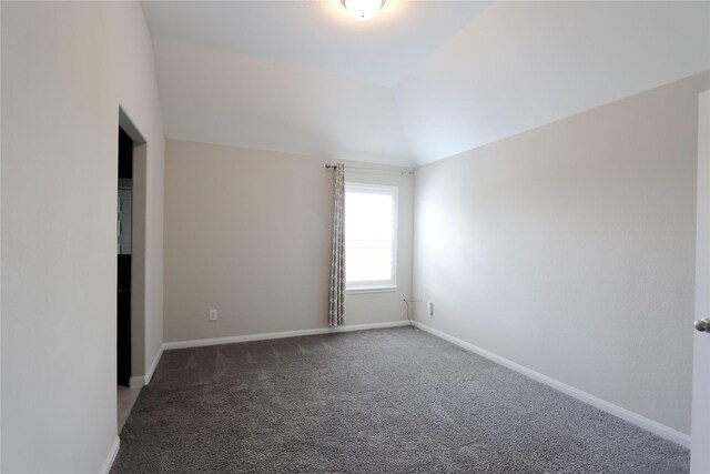 spare room with baseboards, vaulted ceiling, and carpet
