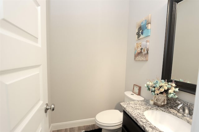 bathroom with vanity, baseboards, wood finished floors, and toilet
