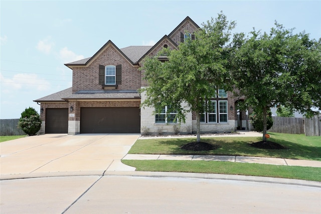 craftsman-style home with a garage, brick siding, fence, a front lawn, and concrete driveway