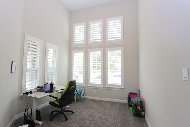 carpeted home office with baseboards and a towering ceiling