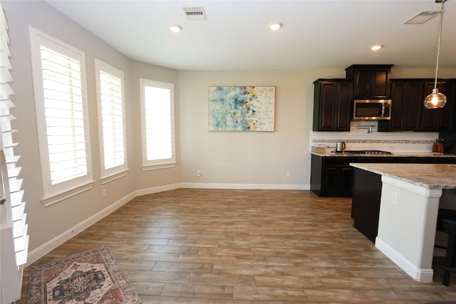 kitchen featuring stainless steel microwave, visible vents, pendant lighting, and light wood-style floors