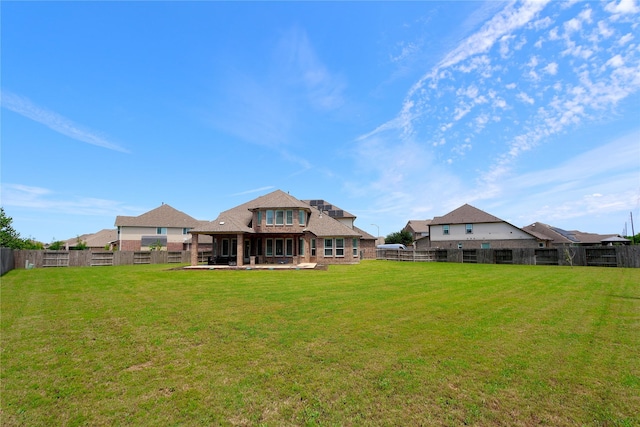 rear view of property with a fenced backyard, a yard, a patio area, and brick siding