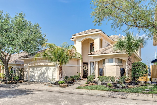 mediterranean / spanish-style house featuring stucco siding, a tile roof, concrete driveway, and an attached garage
