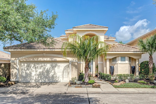 mediterranean / spanish-style home featuring driveway, a garage, stucco siding, and a tiled roof