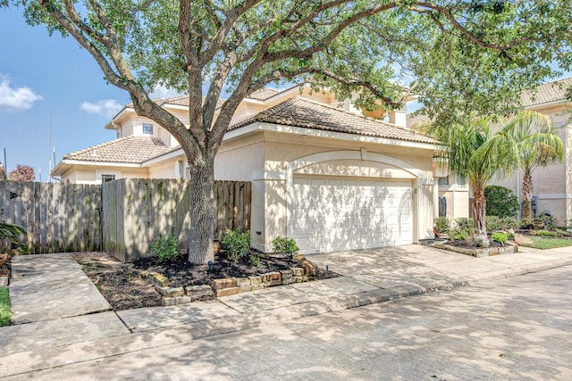 view of front of home with fence, concrete driveway, stucco siding, and a garage
