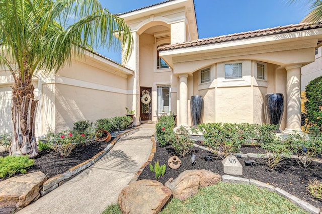 entrance to property featuring a tile roof and stucco siding