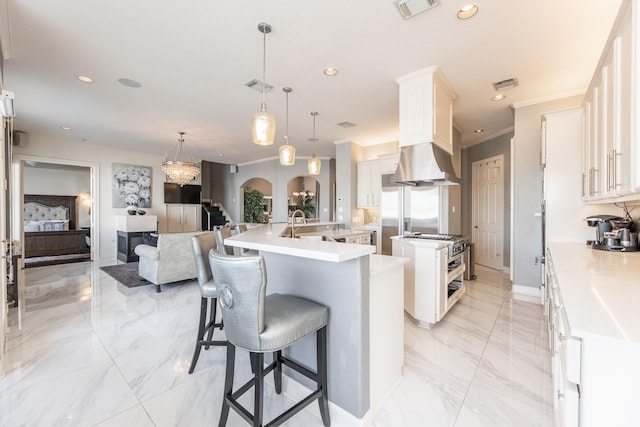kitchen with recessed lighting, island range hood, a large island with sink, and marble finish floor