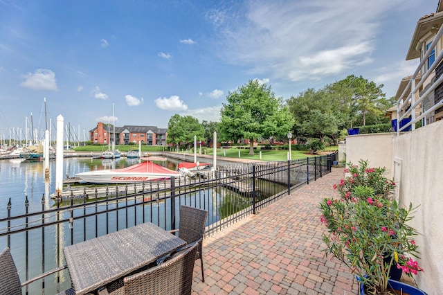 view of patio / terrace featuring boat lift, fence, a boat dock, and a water view