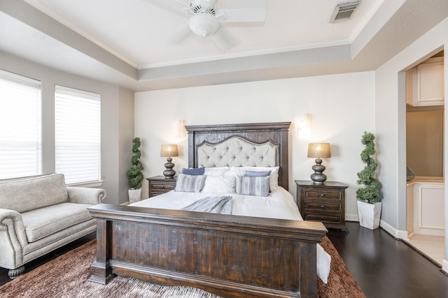 bedroom with visible vents, a raised ceiling, wood finished floors, and ornamental molding