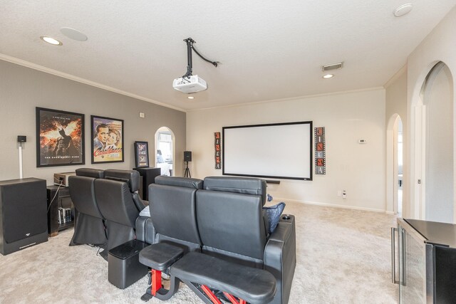 home theater room featuring visible vents, light carpet, crown molding, and arched walkways