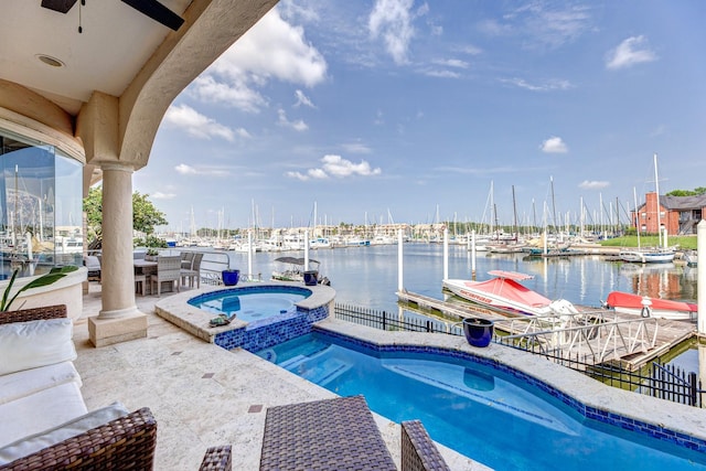 view of pool featuring a dock, a water view, ceiling fan, and a pool with connected hot tub