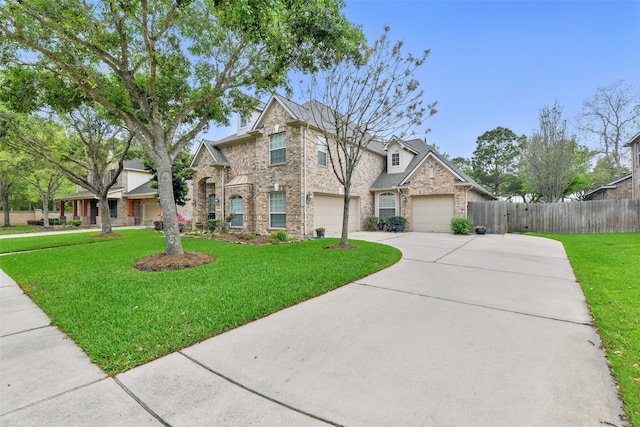 view of front of home with brick siding, fence, a garage, driveway, and a front yard
